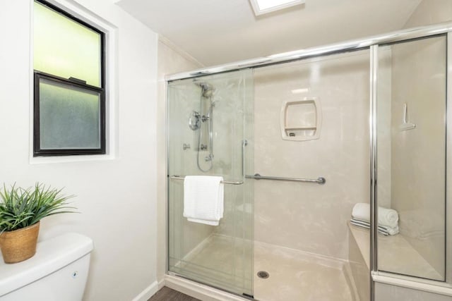 bathroom featuring a shower with shower door and toilet