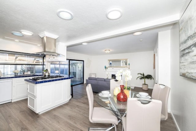 kitchen with stainless steel gas cooktop, white cabinetry, a center island, dishwasher, and island exhaust hood