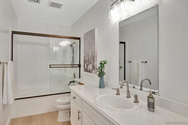 full bathroom featuring toilet, bath / shower combo with glass door, hardwood / wood-style flooring, and vanity