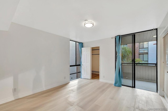 unfurnished room featuring light wood-type flooring and a baseboard heating unit