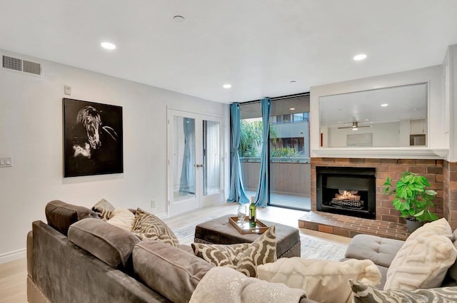 living room with light hardwood / wood-style floors, floor to ceiling windows, ceiling fan, and a fireplace