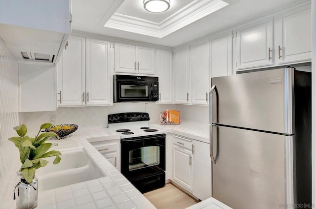 kitchen featuring white cabinets, tile counters, white electric range, stainless steel refrigerator, and crown molding