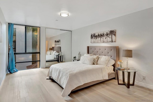 bedroom with hardwood / wood-style floors, expansive windows, and a closet