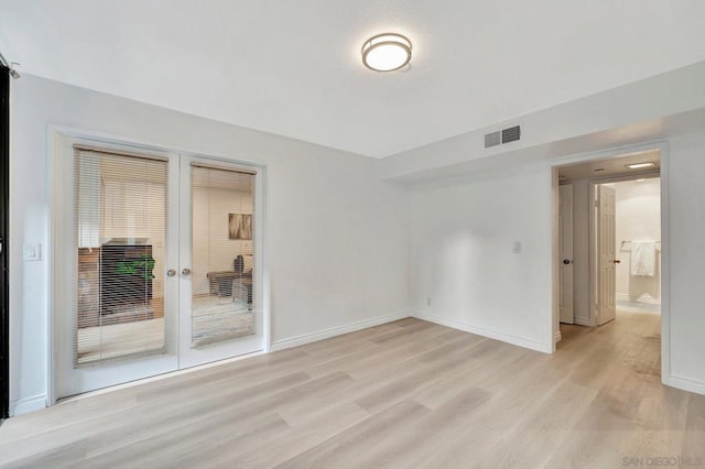 empty room with light hardwood / wood-style floors and french doors