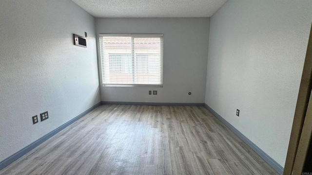 empty room with light hardwood / wood-style floors and a textured ceiling