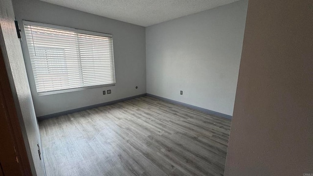 unfurnished room featuring wood-type flooring and a textured ceiling