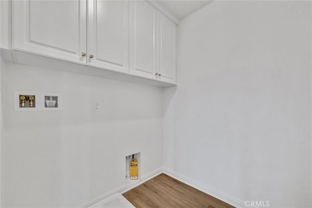 laundry room with washer hookup, hardwood / wood-style flooring, and cabinets