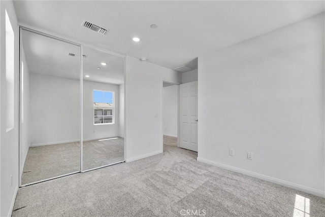 unfurnished bedroom featuring light carpet and a closet