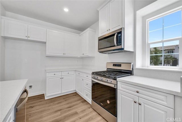 kitchen with white cabinets, appliances with stainless steel finishes, and light hardwood / wood-style flooring