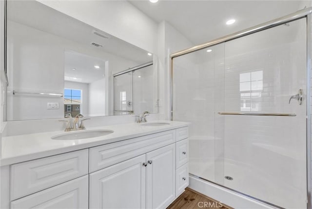 bathroom featuring hardwood / wood-style flooring, an enclosed shower, and vanity