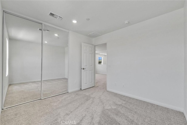 unfurnished bedroom featuring a closet and light carpet