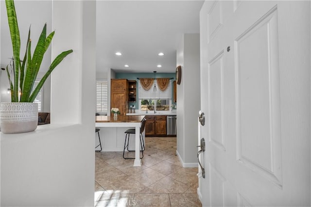 kitchen with light tile patterned floors, dishwasher, and a breakfast bar area