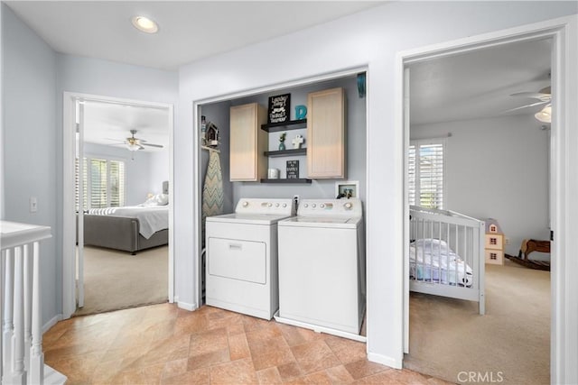 laundry room featuring washer and clothes dryer, light colored carpet, a healthy amount of sunlight, and cabinets