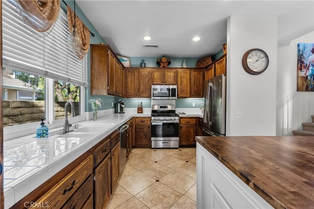 kitchen with light tile patterned floors, wood counters, appliances with stainless steel finishes, and sink