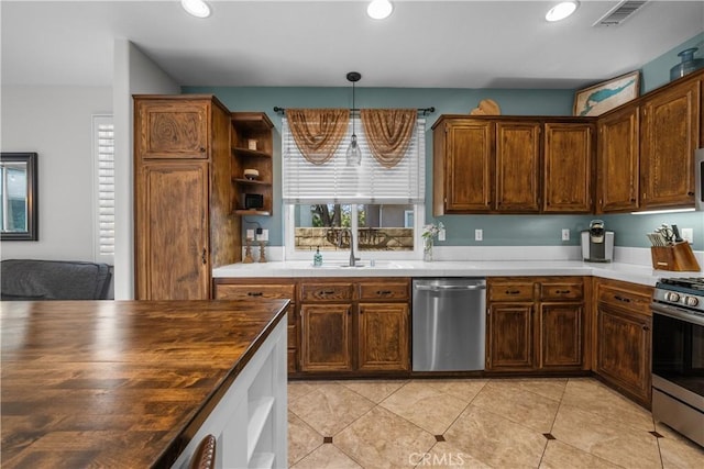 kitchen with stainless steel appliances, sink, hanging light fixtures, butcher block countertops, and light tile patterned floors