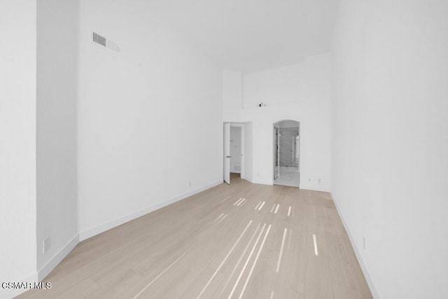 empty room with light hardwood / wood-style floors and a high ceiling