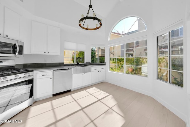 kitchen with decorative light fixtures, white cabinets, appliances with stainless steel finishes, and sink