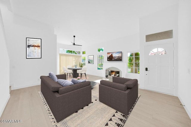 living room featuring ceiling fan, a towering ceiling, and light hardwood / wood-style flooring