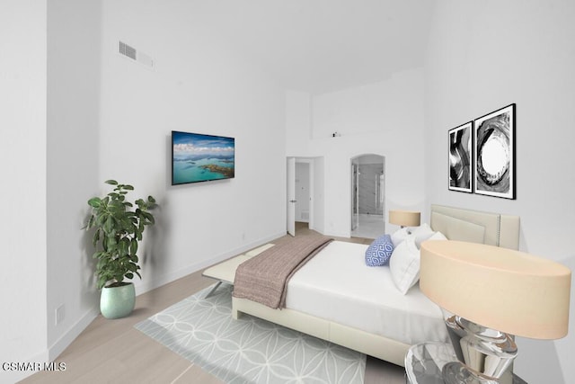 bedroom featuring light hardwood / wood-style flooring and a towering ceiling