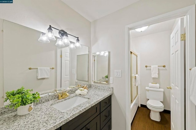 full bathroom featuring bath / shower combo with glass door, toilet, vanity, and hardwood / wood-style floors