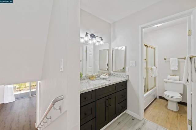 full bathroom featuring toilet, combined bath / shower with glass door, hardwood / wood-style flooring, and vanity