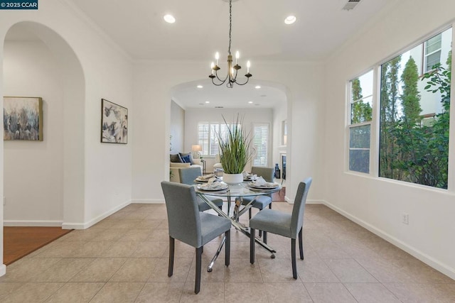 tiled dining room featuring ornamental molding and an inviting chandelier