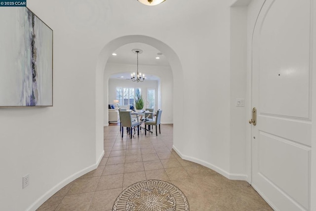 corridor with light tile patterned floors and a chandelier