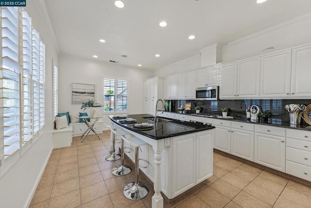 kitchen featuring white cabinets, a kitchen island with sink, appliances with stainless steel finishes, and light tile patterned floors