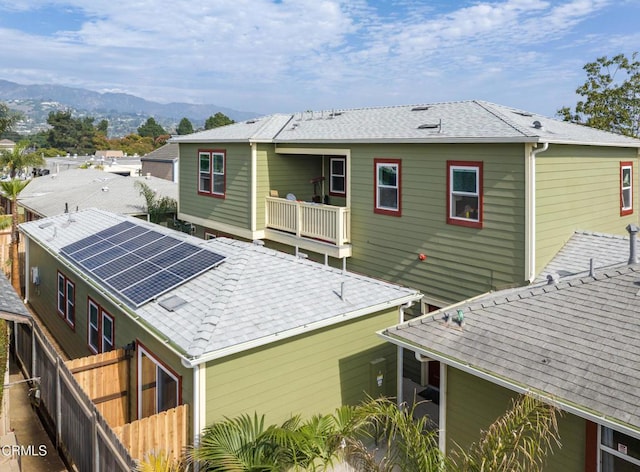 back of property with a mountain view and solar panels