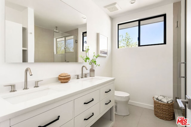 bathroom featuring toilet, vanity, a shower with door, and tile patterned floors