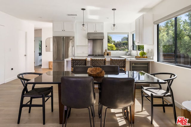 dining area featuring wine cooler, sink, and light hardwood / wood-style flooring