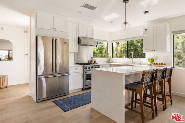 kitchen featuring white cabinets, premium appliances, and pendant lighting