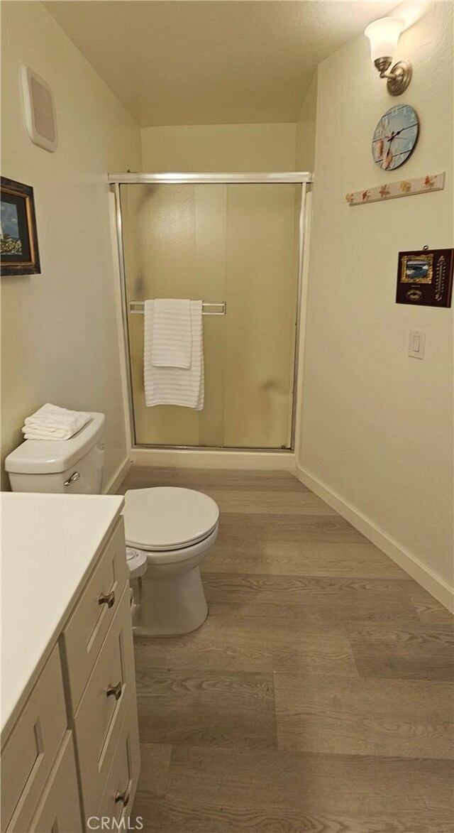 bathroom with vanity, toilet, a shower with shower door, and hardwood / wood-style floors