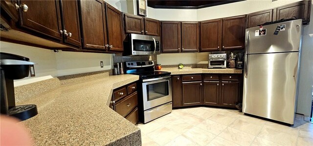 kitchen featuring light stone countertops, appliances with stainless steel finishes, and dark brown cabinetry