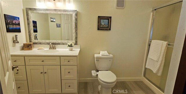 bathroom with vanity, wood-type flooring, a shower with door, and toilet