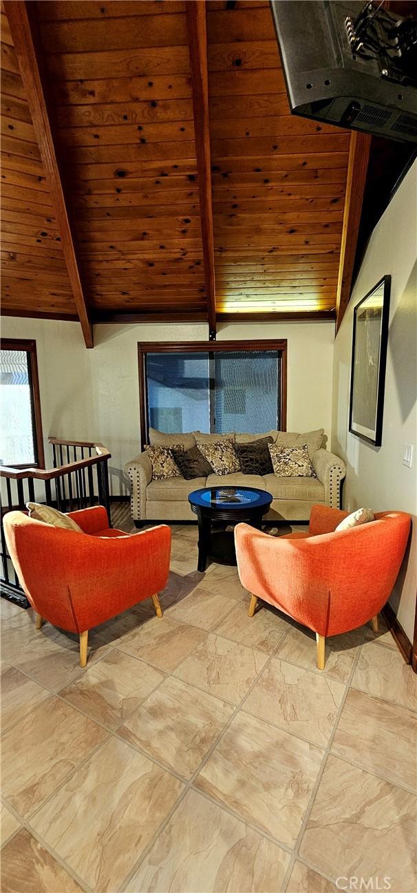 living room with vaulted ceiling with beams and wood ceiling