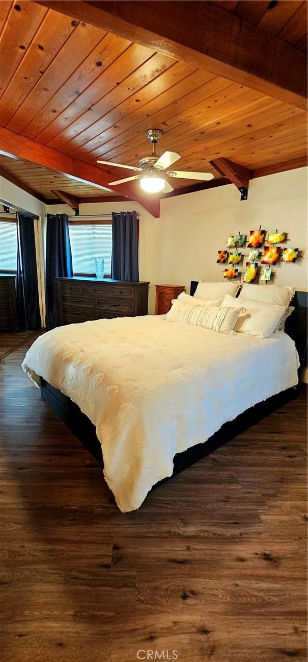 bedroom with beamed ceiling, ceiling fan, dark hardwood / wood-style floors, and multiple windows