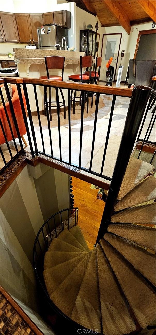 stairway with beamed ceiling and wood-type flooring