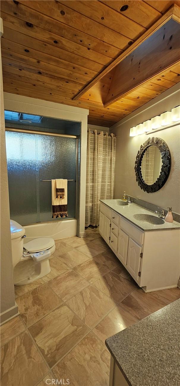 full bathroom with vanity, wooden ceiling, shower / bath combination with glass door, and toilet