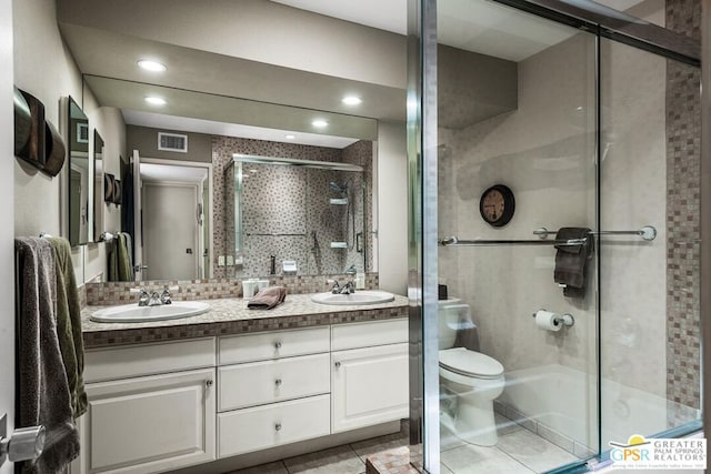 bathroom featuring toilet, vanity, tile patterned flooring, decorative backsplash, and a shower with shower door