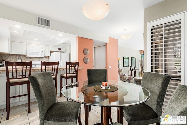 tiled dining area with a tray ceiling