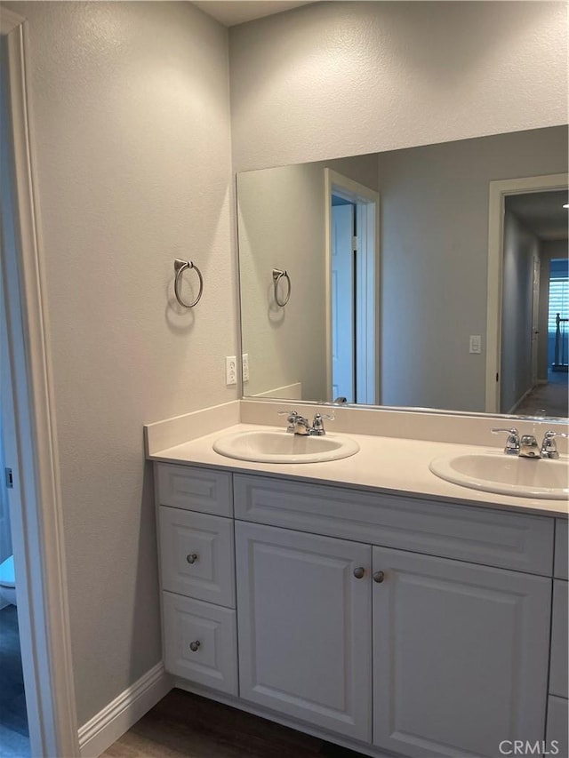 bathroom with a sink, baseboards, and double vanity