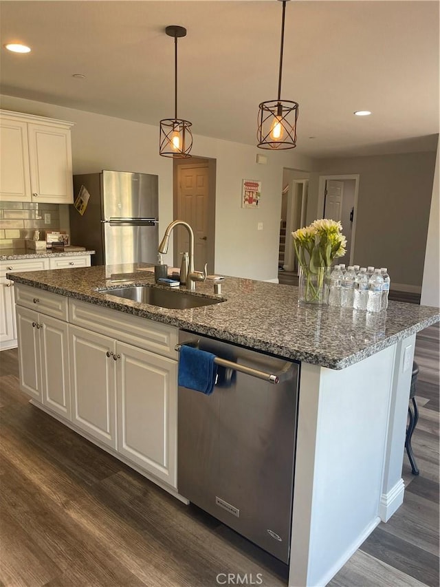 kitchen with dark wood-style floors, appliances with stainless steel finishes, a sink, and a kitchen island with sink