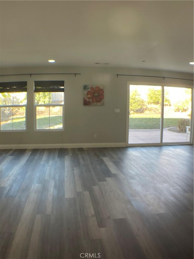 spare room featuring a healthy amount of sunlight, baseboards, and wood finished floors