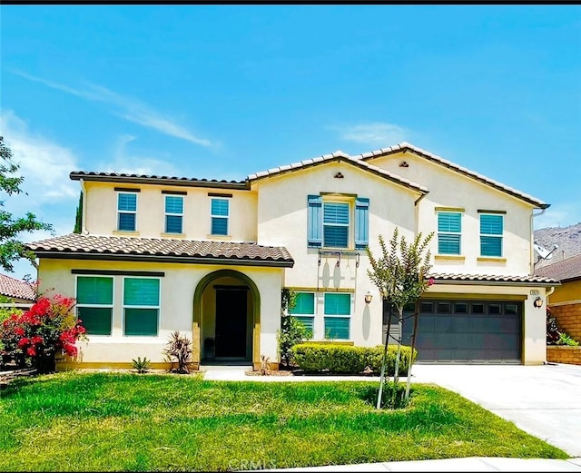 mediterranean / spanish home with a garage, a tile roof, driveway, stucco siding, and a front lawn