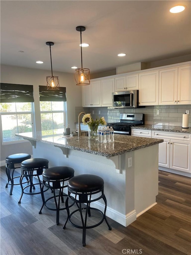 kitchen with appliances with stainless steel finishes, white cabinetry, a sink, and dark wood-type flooring