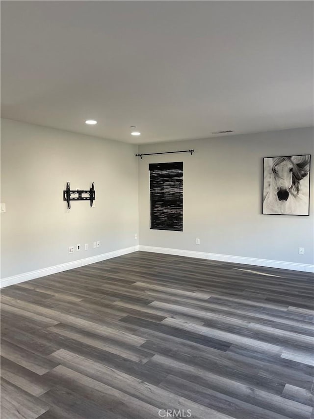 empty room with dark wood-type flooring, recessed lighting, and baseboards