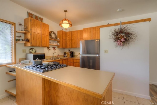 kitchen with light tile patterned floors, kitchen peninsula, appliances with stainless steel finishes, hanging light fixtures, and sink