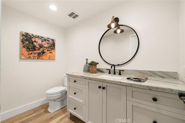 bathroom with hardwood / wood-style flooring, vanity, and toilet