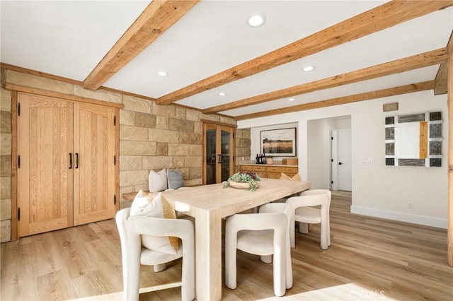 dining space with beamed ceiling and light hardwood / wood-style flooring